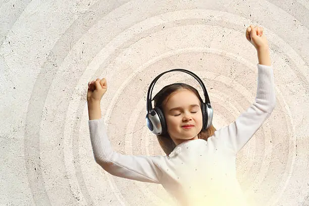 Little girl in headphones with eyes closed enjoying music