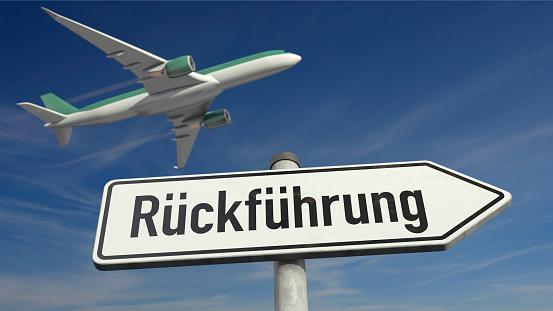 Return of asylum seekers by plane - Guide post with the German word 