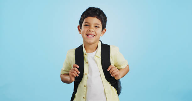 school, happy or face of child in studio on blue background ready for class, learning and education. student, smile or portrait of a young boy with bag excited for lesson, academy or kindergarten - backpack student report card education imagens e fotografias de stock