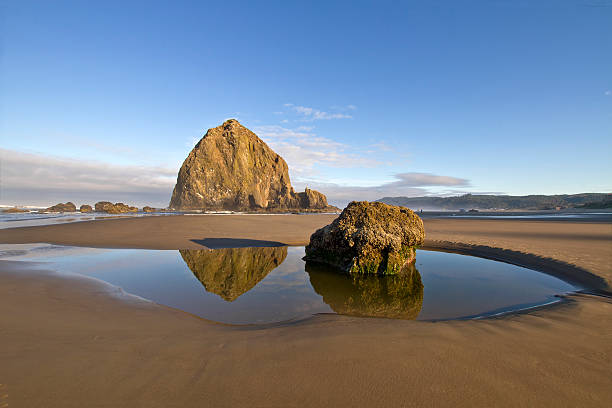 riflesso dell'haystack rock di cannon beach - reflection water rock beach foto e immagini stock