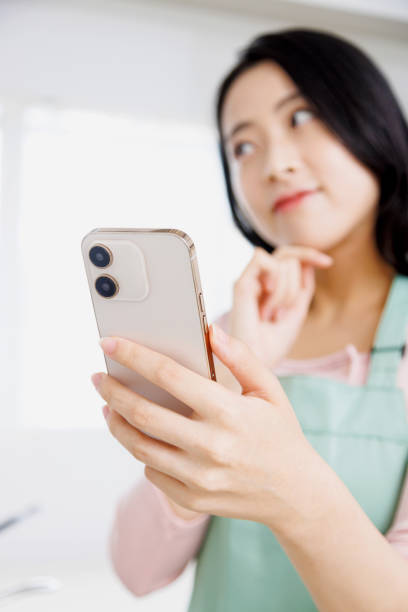 istock Asian woman using a mobile phone in the kitchen 1837033707