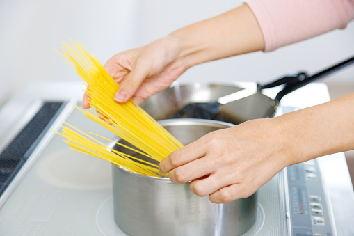Woman cooking spaghetti in the kitchen