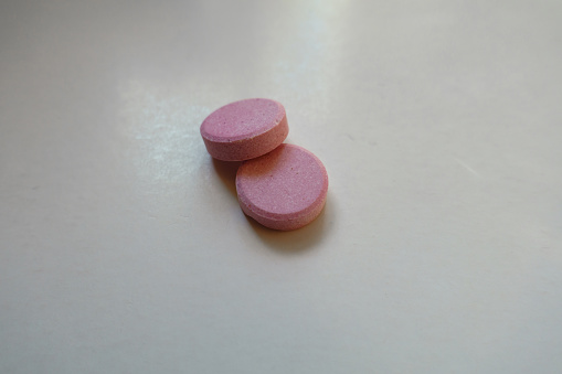 Close shot of two big pink oral probiotic tablets