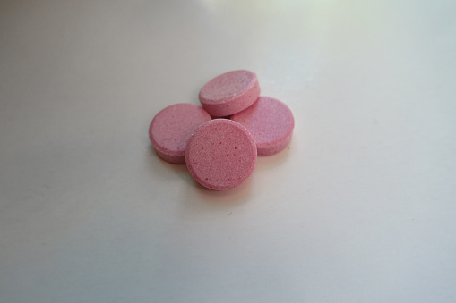 Close view of four big pink oral probiotic tablets
