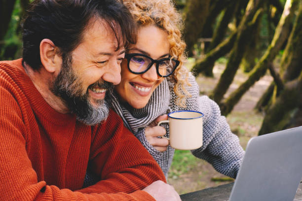 istock Happy modern couple use together laptop computer outdoors with trees and woods in background - video call and smart remote working activity lifestyle concept with cheerful people and technology 1837064581