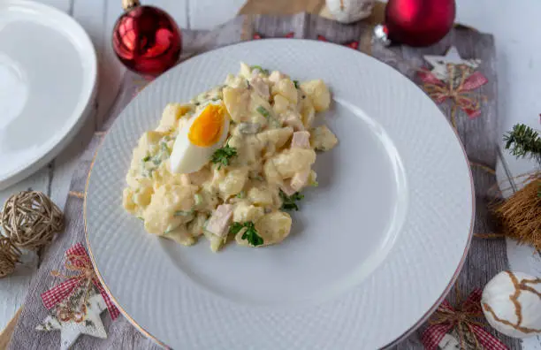Traditional fresh and homemade german potato salad for christmas eve dinner. Served ready to eat for side dish on a festive plate on christmas table background.