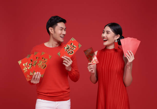 feliz año nuevo chino. pareja asiática con ropa roja que sostiene angpao o paquete rojo regalo monetario aislado sobre fondo rojo. el texto chino significa gran suerte, gran felicidad. - currency envelope luck new fotografías e imágenes de stock