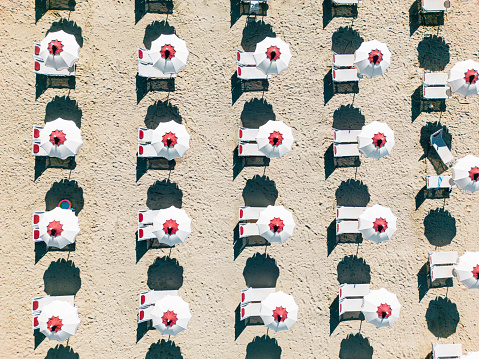 Aerial view of many beach umbrellas on the beach. White and red umbrellas.