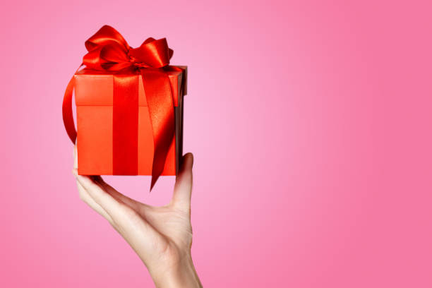 istock Hand holding red gift box with red bow isolated on pink background. copy space 1837167595