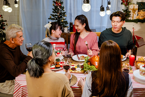 Happy and Cheerful group of extended Asian family. Granddaughter talking and smiling with grandparent and mother during Christmas dinner at home. Celebration holiday. Family gatherings and reunions.