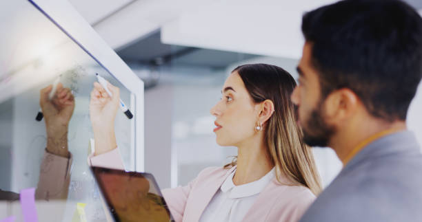 istock Business people, teamwork and planning notes on glass in strategy meeting, feedback or collaboration. Man, woman and brainstorming project ideas, timeline process or calendar schedule of target goals 1837210148