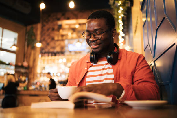 istock young black man in cafe reading book 1837243013