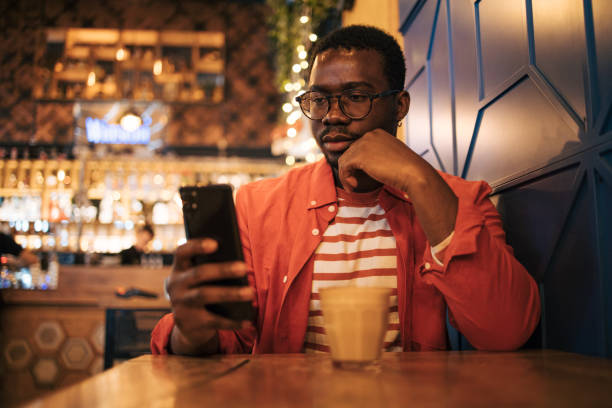 istock young black man in cafe using phone 1837258046