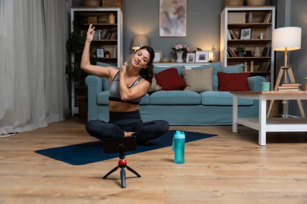 istock Attractive young woman learning new exercises watching online workout tutorials over her phone at home. Handsome female practicing yoga class having video call over smartphone with clients on internet 1837289862