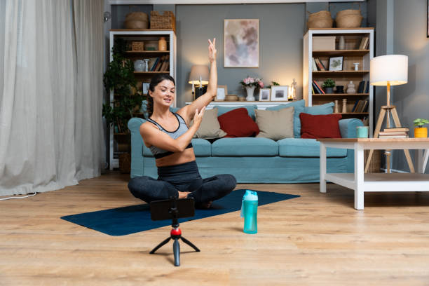 istock Attractive young woman learning new exercises watching online workout tutorials over her phone at home. Handsome female practicing yoga class having video call over smartphone with clients on internet 1837289889