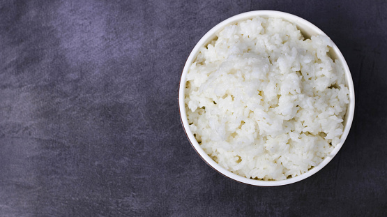 a bowl of white rice on a dark background