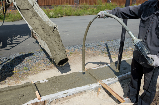 Pouring cement into a wooden formwork for the Foundation of a building that is being built.