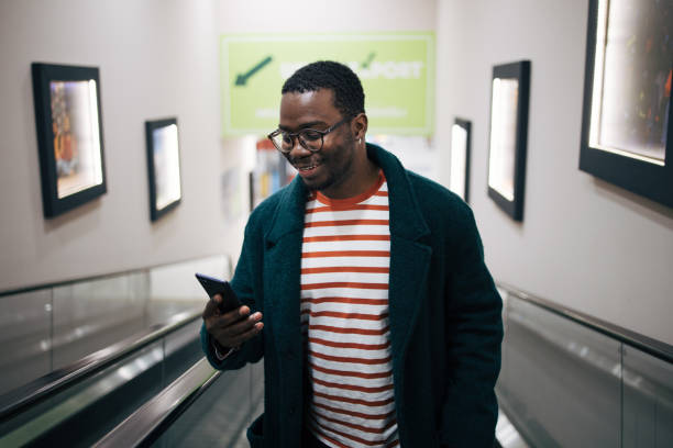 istock Young man standing on an escalator in a shopping mall 1837344154