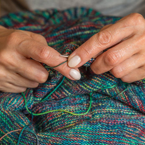 Close up of hands of unrecognizable woman knitting handmade clothes with spokes using  wool yarn. Concept of leisure activity.Knitting from yarn on  coarse spokes. Close up of hands of unrecognizable woman knitting handmade clothes with spokes using  wool yarn. Concept of leisure activity.Knitting from yarn on  coarse spokes. needles eye stock pictures, royalty-free photos & images