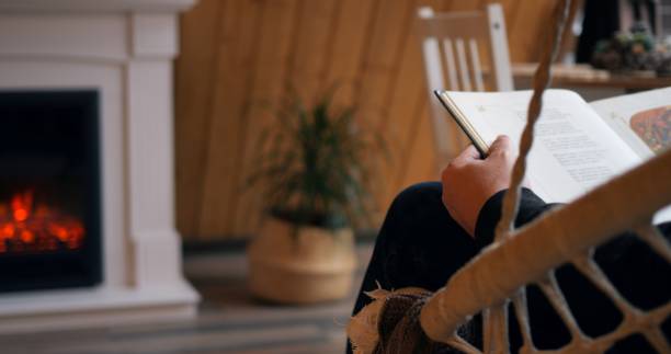 istock Man by fireplace engrossed in book, procrastination theme evident. Cozy setting enhances procrastination feel. Procrastination captured perfectly in leisurely scene. Cozy home concept 1837364529