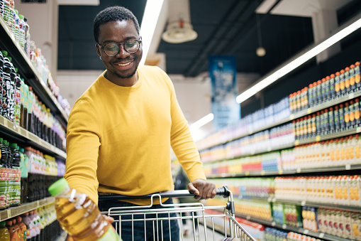 Young black man takes juice from the supermarket shelf