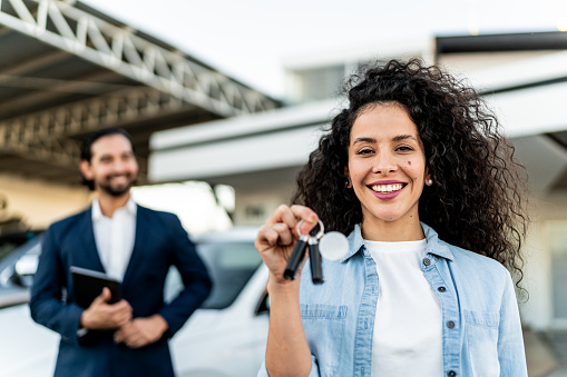 Portrait of a mid adult woman holding a car key at dealership