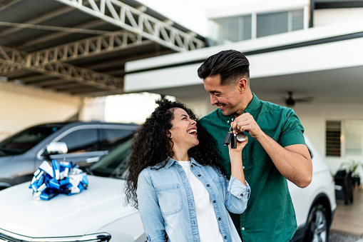 Mid adult couple celebrating after buy a car at dealership
