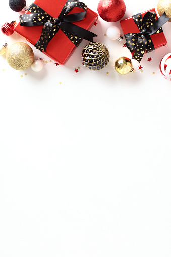 Christmas vertical background.. Flat lay red gift boxes with black ribbon bows, glitter red, black and golden balls, decorations on white table. View from above