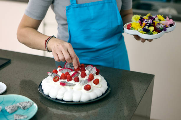 femme ajoutant des fleurs comestibles à un gâteau - baking cake making women photos et images de collection