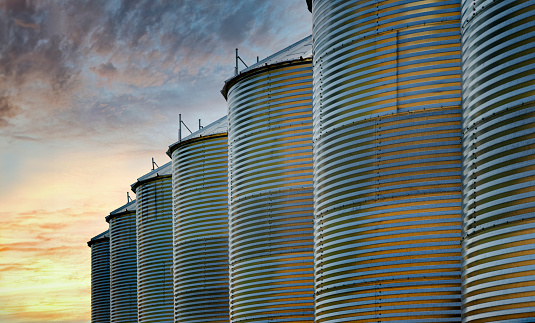 A row of grain silos silhouetted against a sunset