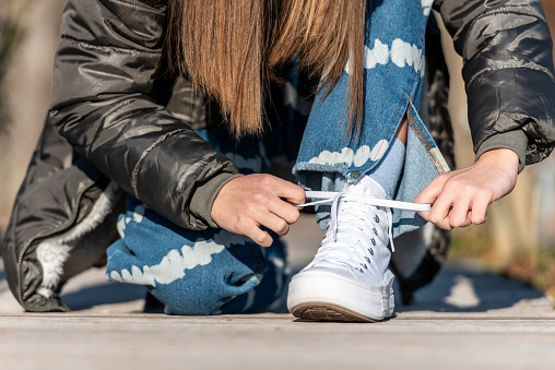 Teenage Girl on the Street Tying White Sneakers
