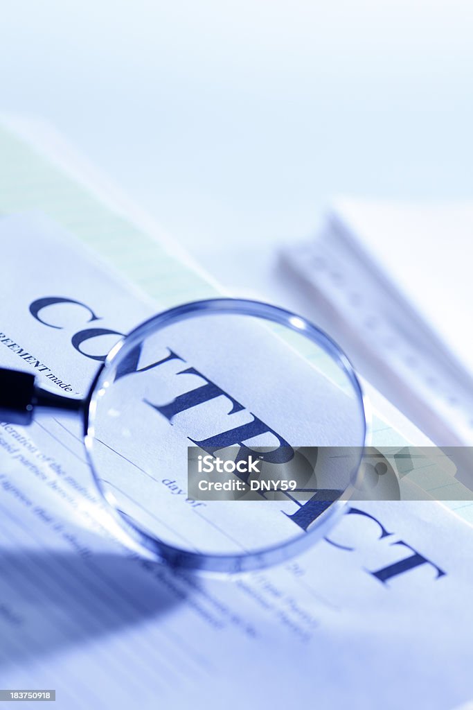 Contract A magnifying glass examining a contract. Agreement Stock Photo