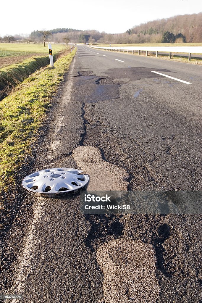 Radkappe auf einer beschädigten Road - Lizenzfrei Holprig Stock-Foto