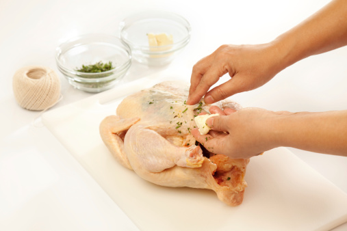 seasoning whole chicken with herbs and butter before roasting.THIS IMAGE IS ONLY AVAILABLE HERE AT ISTOCKPHOTO