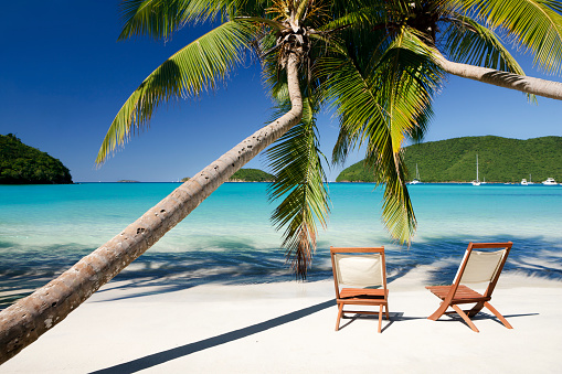 two teak chairs under palm trees at a perfect beach in St. John, US Virgin Islands