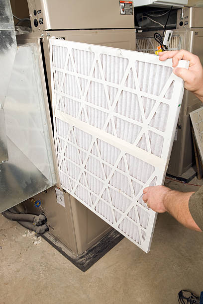 hombre manos cambio grande plegado horno de filtro de aire - furnace fotografías e imágenes de stock