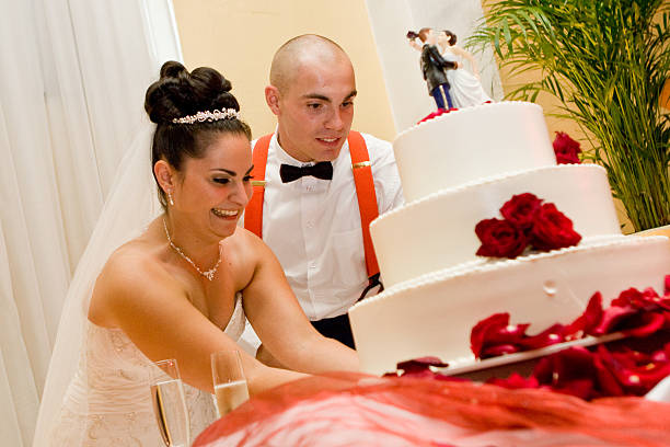 istock Bride and Groom cutting three tiered wedding cake red white 183754426