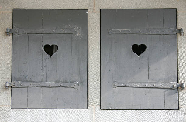 Very old wooden window shutters with heart symbols cut out of the wood. Photographed in Switzerland.