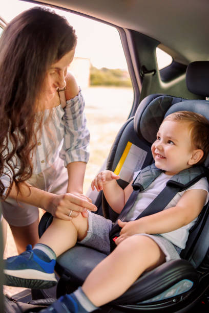 mutter schnallt kleinkind in eine babyschale - seat belt safety protection driving stock-fotos und bilder