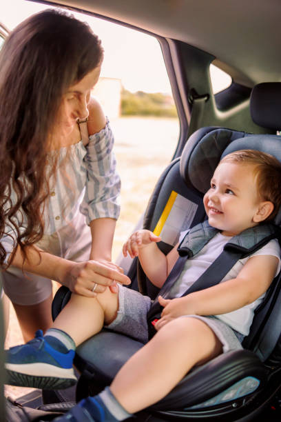 мать пристегивает маленького сына в детском автокресле - seat belt safety protection driving стоковые фото и изображения