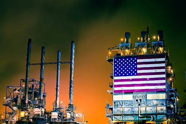 A massive United States flag is draped across the central processing unit of an oil refinery near Los Angeles