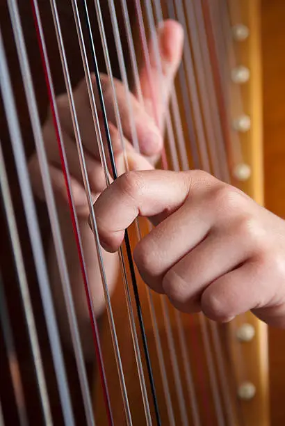 "Detail of hands playing harp, selective focus"