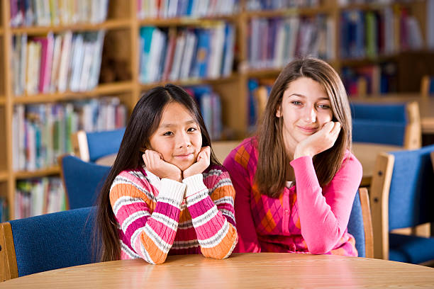 wielorasowe dziewczynki siedzi razem w bibliotece w szkole - sc0460 zdjęcia i obrazy z banku zdjęć