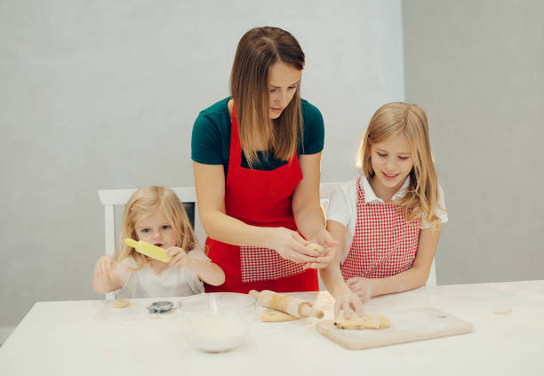 istock Mother and daughters making cookies at kitchen and having fun at home 1837572081