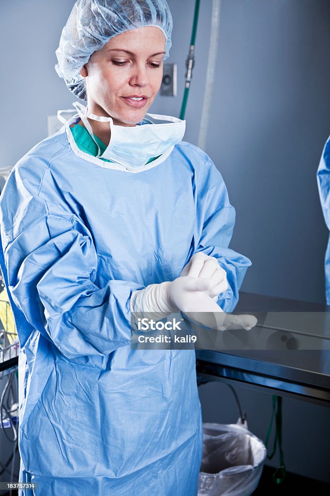 Travailleur médical mise sur des gants en latex - Photo de Blouse de chirurgie libre de droits