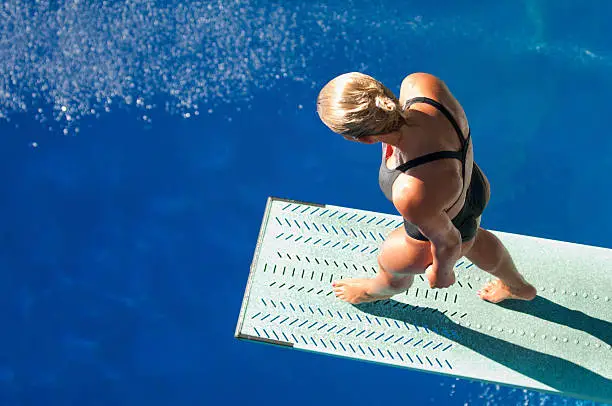 Professional lady diver preparing to dive from the springboard