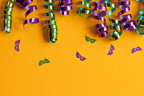 Colorful Background Mardi Gras colors  with ribbon curls and confetti masks on a bright golden yellow background.Please see some similar pictures from my portfolio: mardi gras confetti stock pictures, royalty-free photos & images