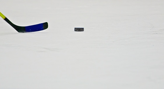 Hockey Stick and Puck on Ice Rink