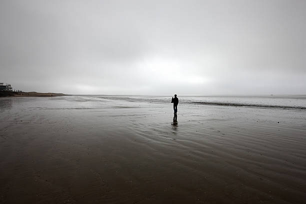 istock Man in silhouette on deserted beach 183758099