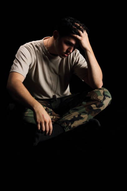 Military Man Depressed Hand on Head Servicemember thinks about his 3rd deployment to the Middle East. military deployment photos stock pictures, royalty-free photos & images